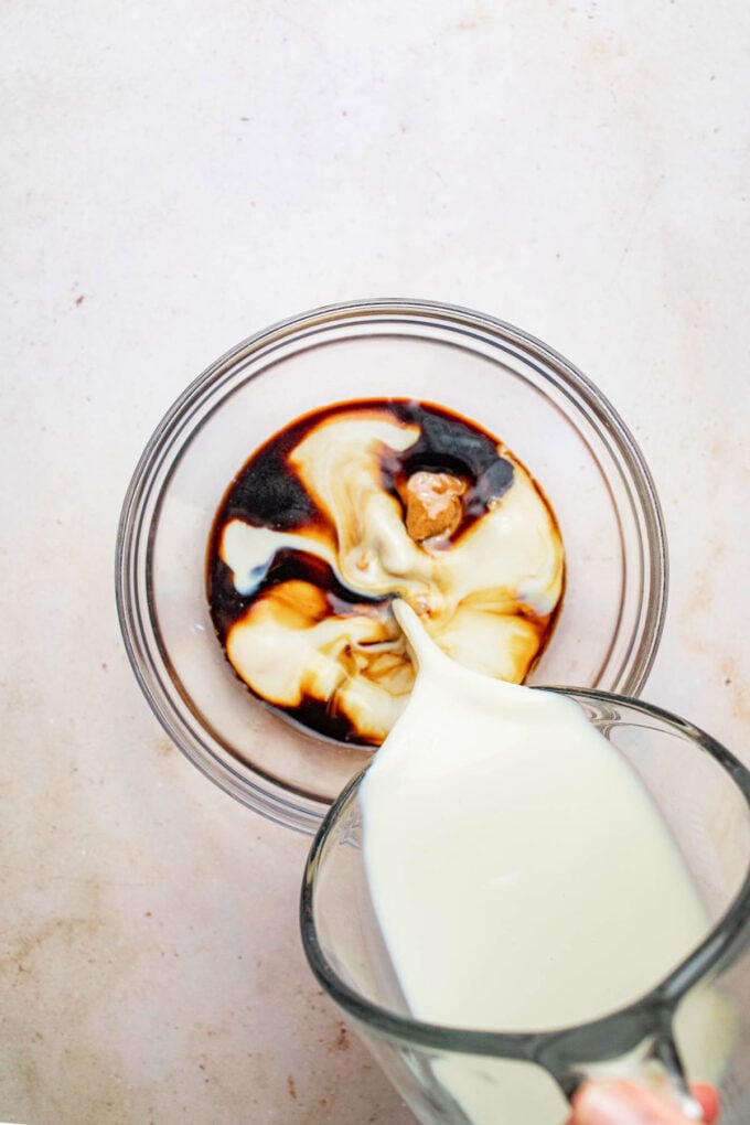 hand pouring soy milk into bowl