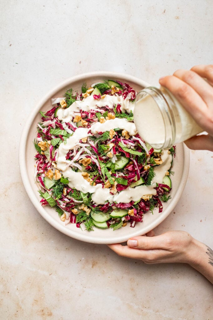 hand pouring dressing over quinoa salad