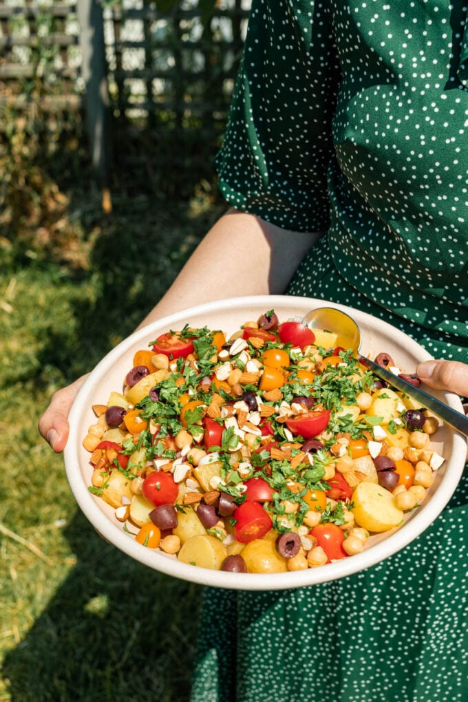 woman in green dress holding potato salad in bowl