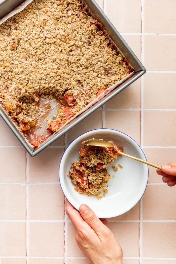 hand scooping rhubarb crisp into bowl