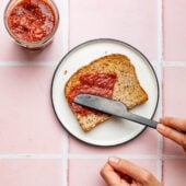 hand spreading chia jam on toast