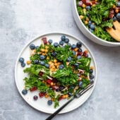 kale and blueberry salad on white plate with fork