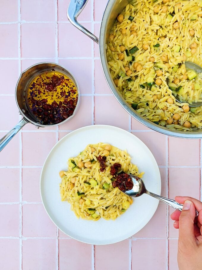 hand with spoon and chiles on pasta