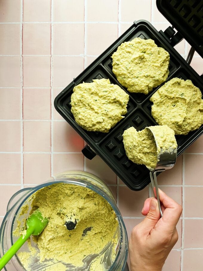 hand pouring waffle batter onto iron