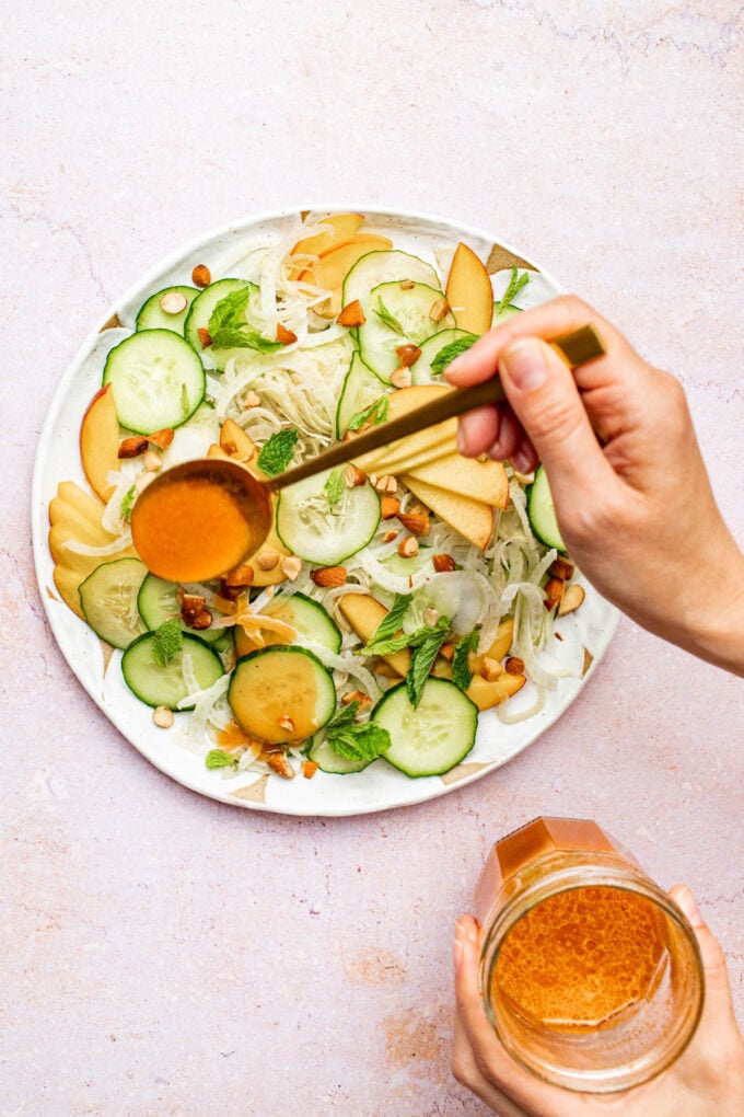 hand pouring dressing on salad