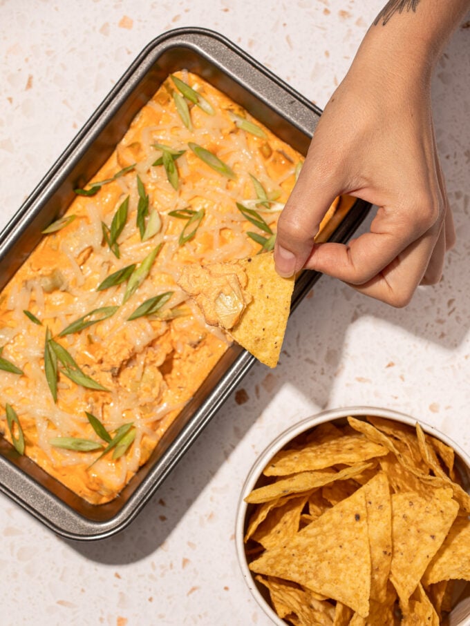 hand dipping chip into buffalo dip