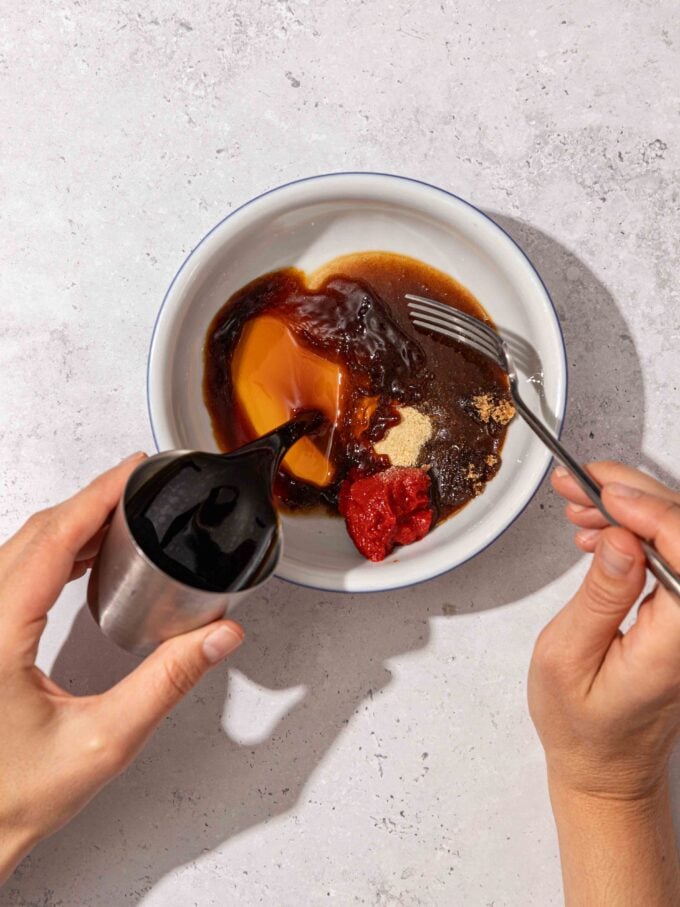 hand pouring soy sauce into bowl