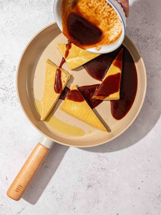 pouring sauce over tofu in skillet