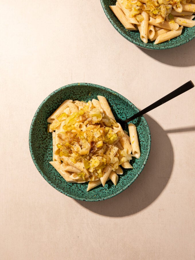 leeks and pasta in blue bowls with black spoon