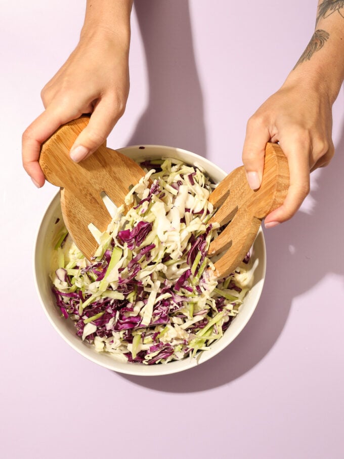 hands tossing coleslaw