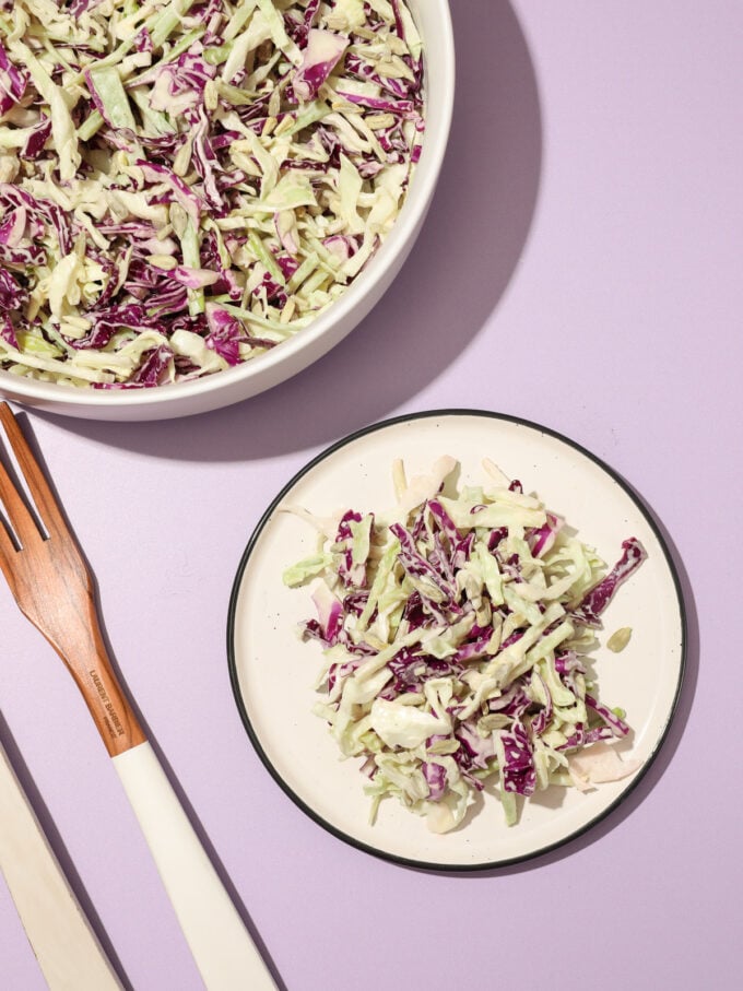 vegan coleslaw on plate with bowl and fork