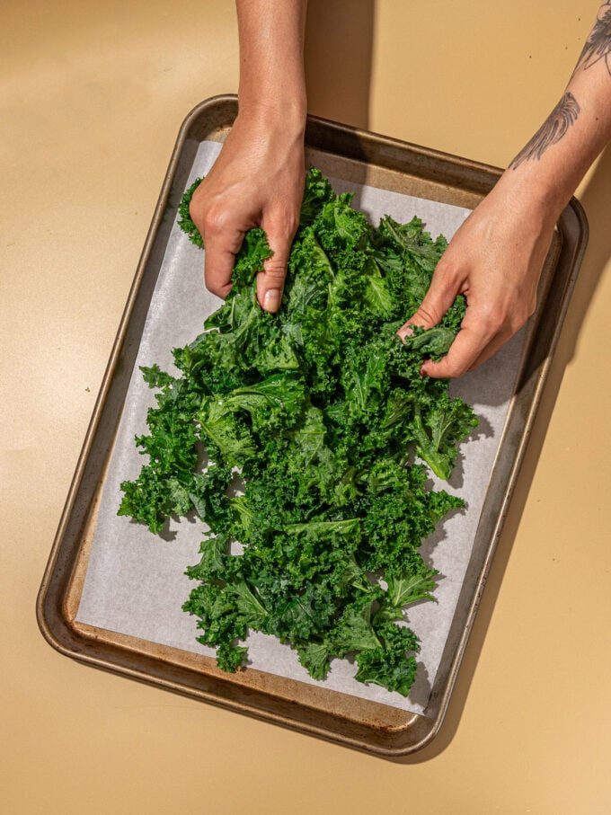 hands massaging kale on cookie sheet