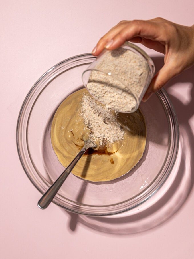 hand adding flour to tahini