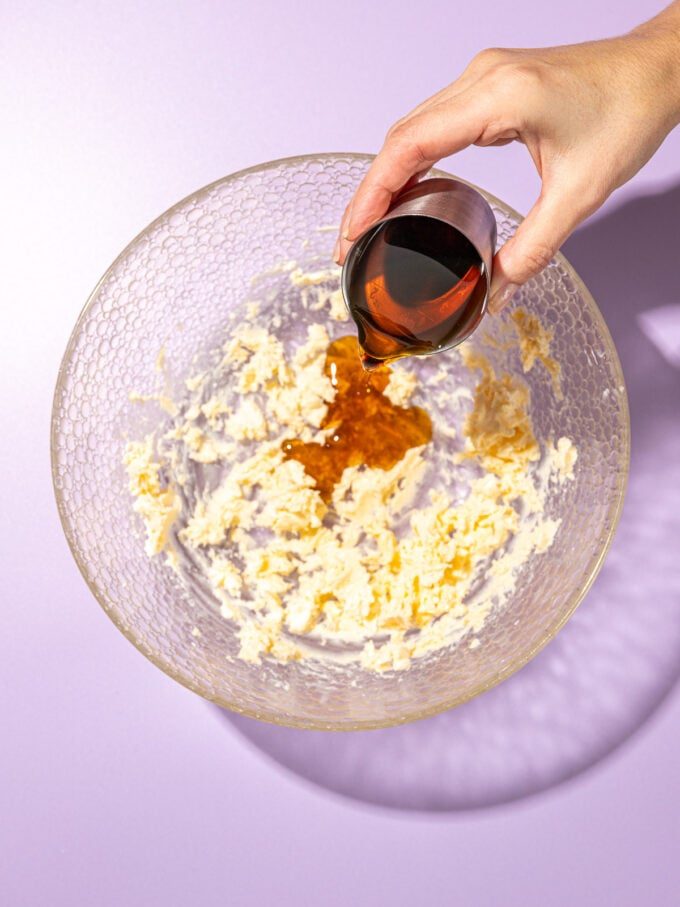 hand pouring maple syrup over butter