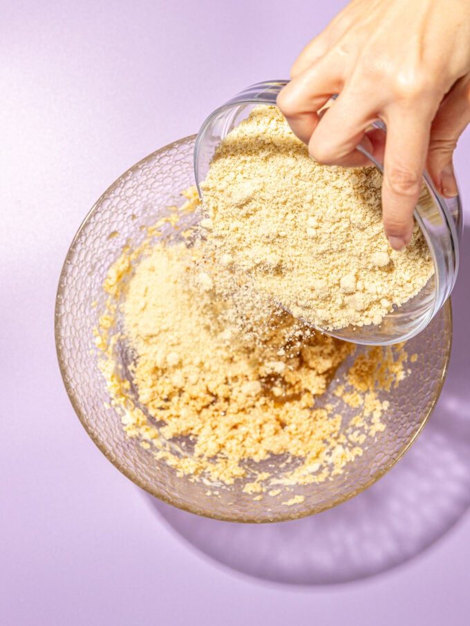 hand pouring almond flour into butter