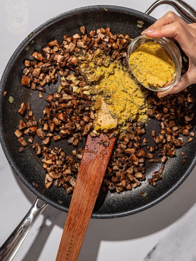 hand shaking seasonings into mushrooms