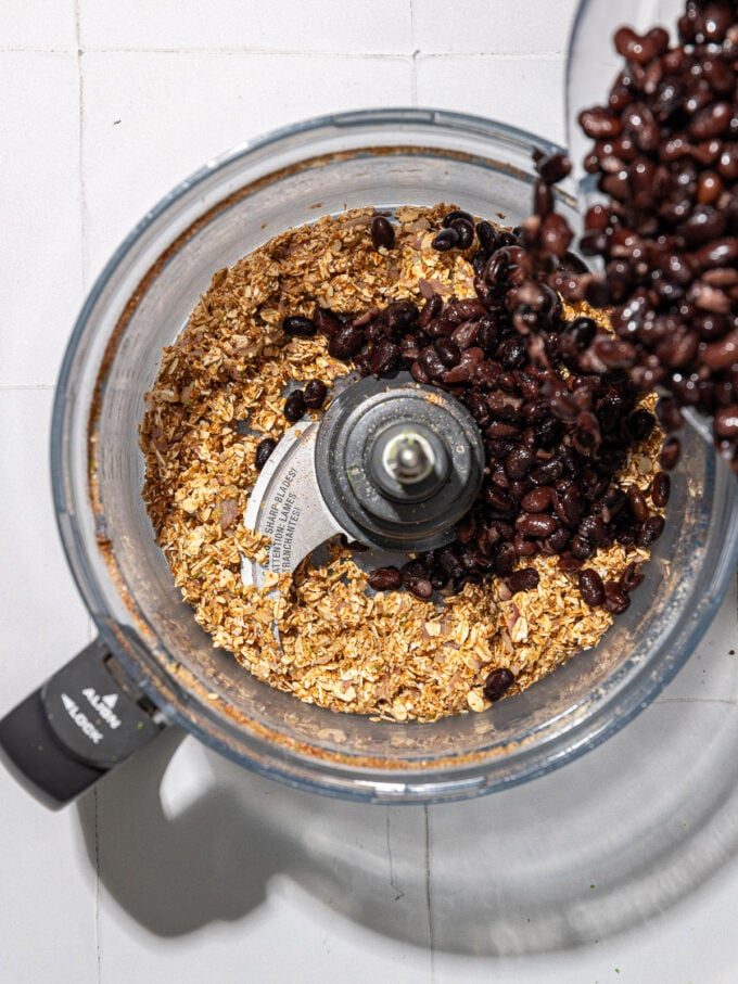 pouring black beans into food processor with oats