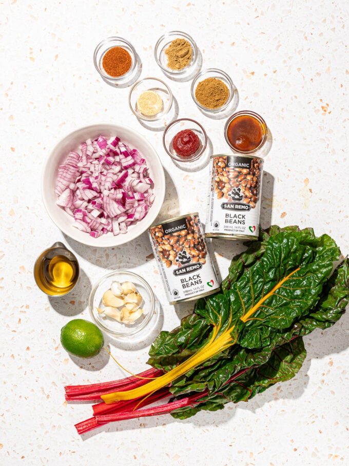 swiss chard, cans of black beans, bowls of red onion and spices