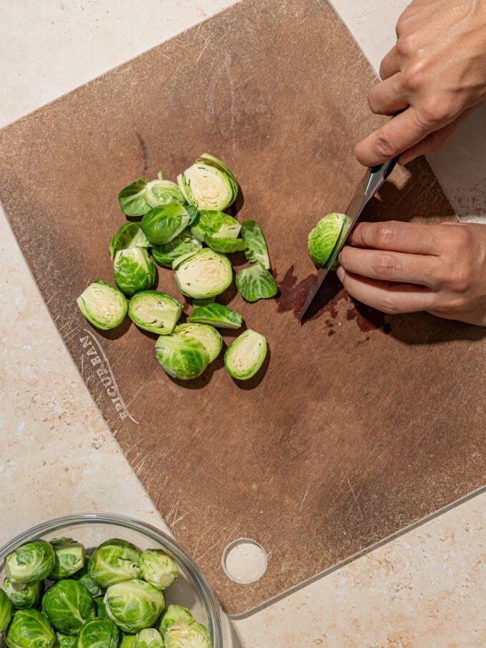hand halving Brussels sprouts on a cutting board