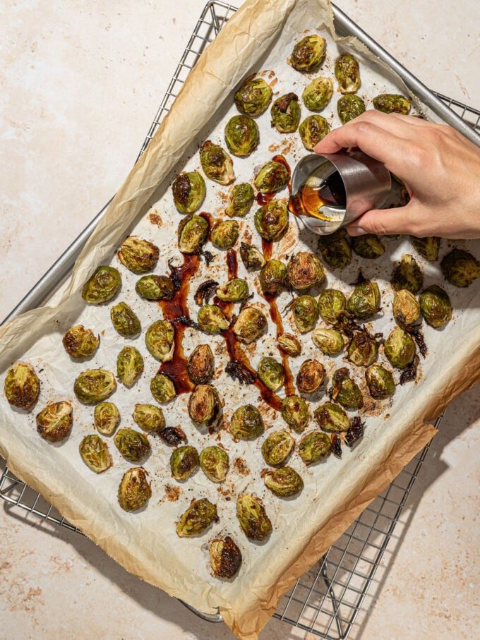 hand pouring maple syrup on roasted brussels sprouts
