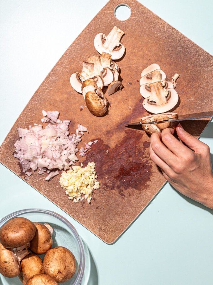 hand slicing mushrooms on cutting board