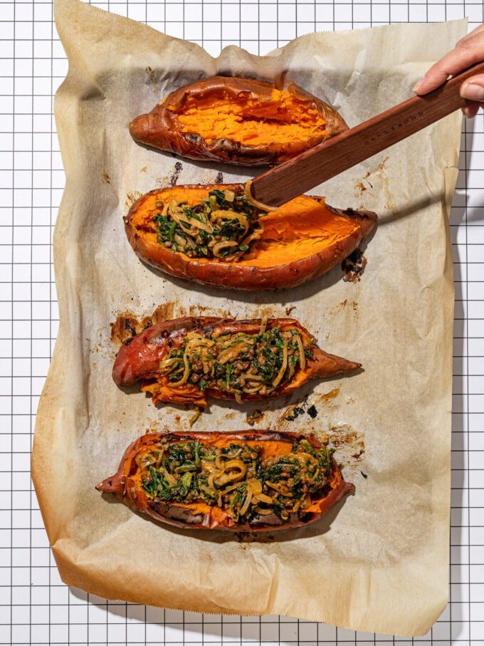 wooden spatula spooning lentil mixture into sweet potatoes