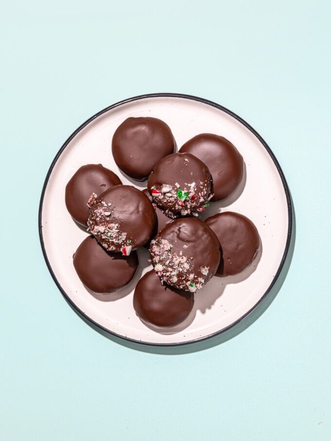 white plate with pile of thin mint cookies on mint background