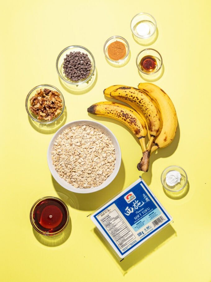 soft tofu, ripe bananas, bowls of oats, walnuts, maple syrup on yellow background
