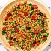 wooden bowl of chickpea salad with olives, tomato and cucumber