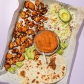 roasted cauliflower, tortillas, cheese, avocado and chipotle sauce on baking sheet