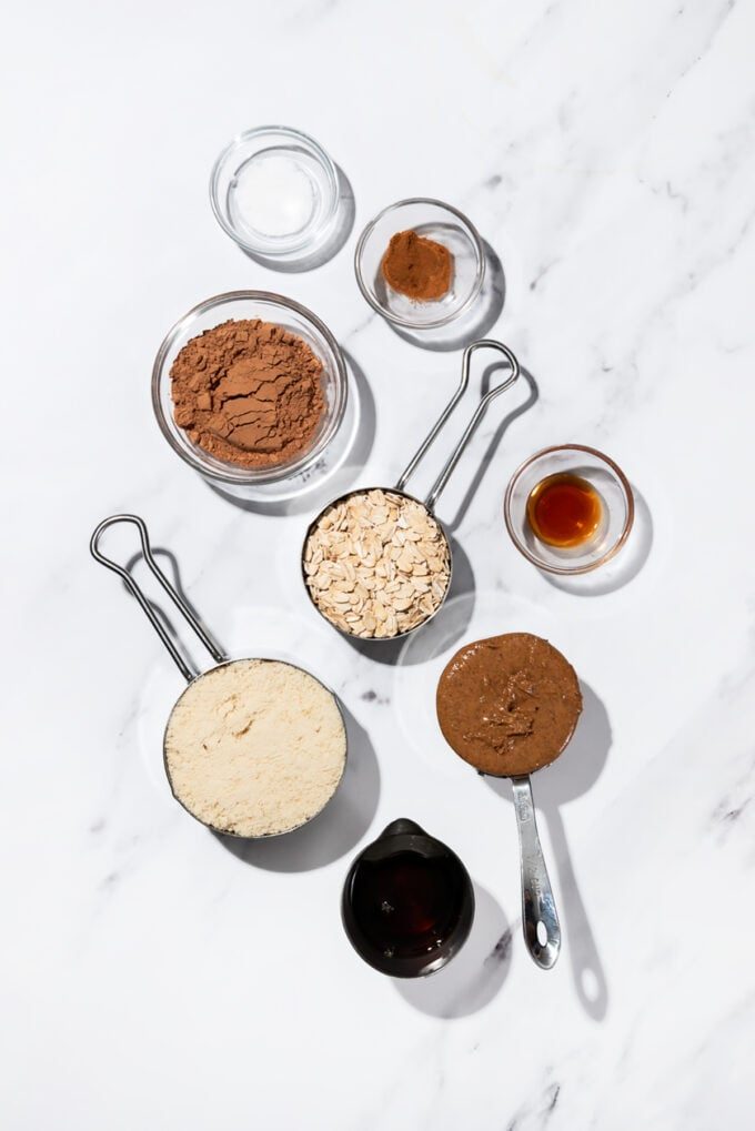 bowls of cocoa powder, almond flour, almond butter, oats and maple syrup