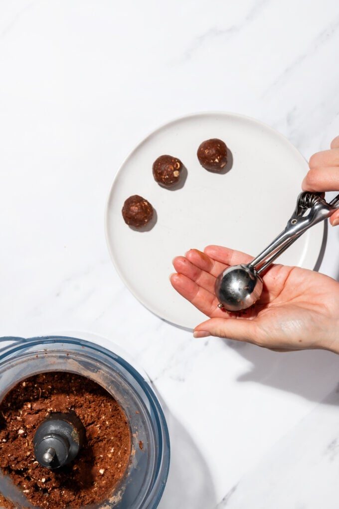 hand scooping protein balls on white plate