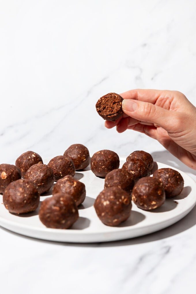 hand holding chocolate protein ball above plate of balls