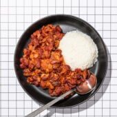 saucy kidney beans with white rice in black bowl with spoon