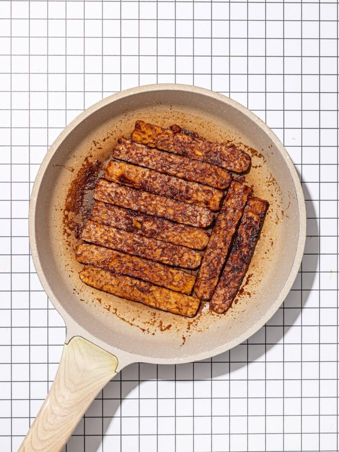 beige skillet with fried tempeh bacon slices