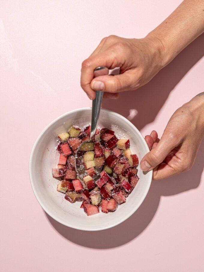 hand stirring rhubarb in white bowl