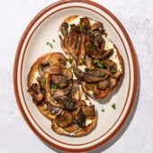 mushrooms on 2 slices of toast on a brown rimmed oblong plate