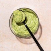 Green goddess dressing in glass bowl with black spoon resting on top
