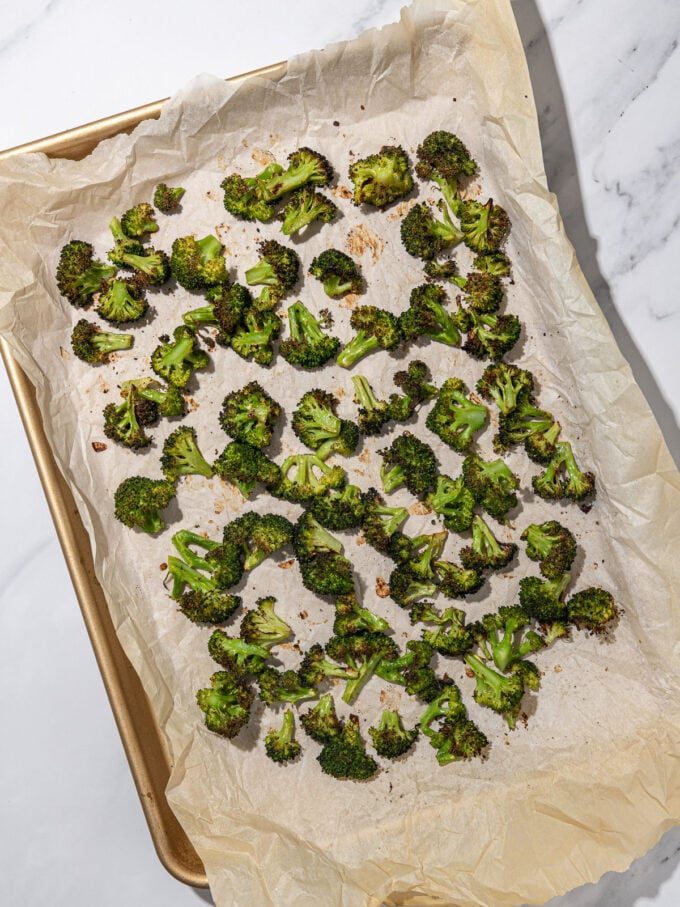 sheet pan, covered in parchment, with roasted broccoli on top