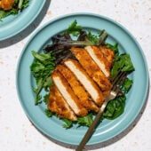 sliced tofu cutlets with salad on blue plates and a black fork