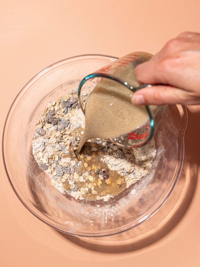 hand pouring wet ingredients into oatmeal raisin cookie mix